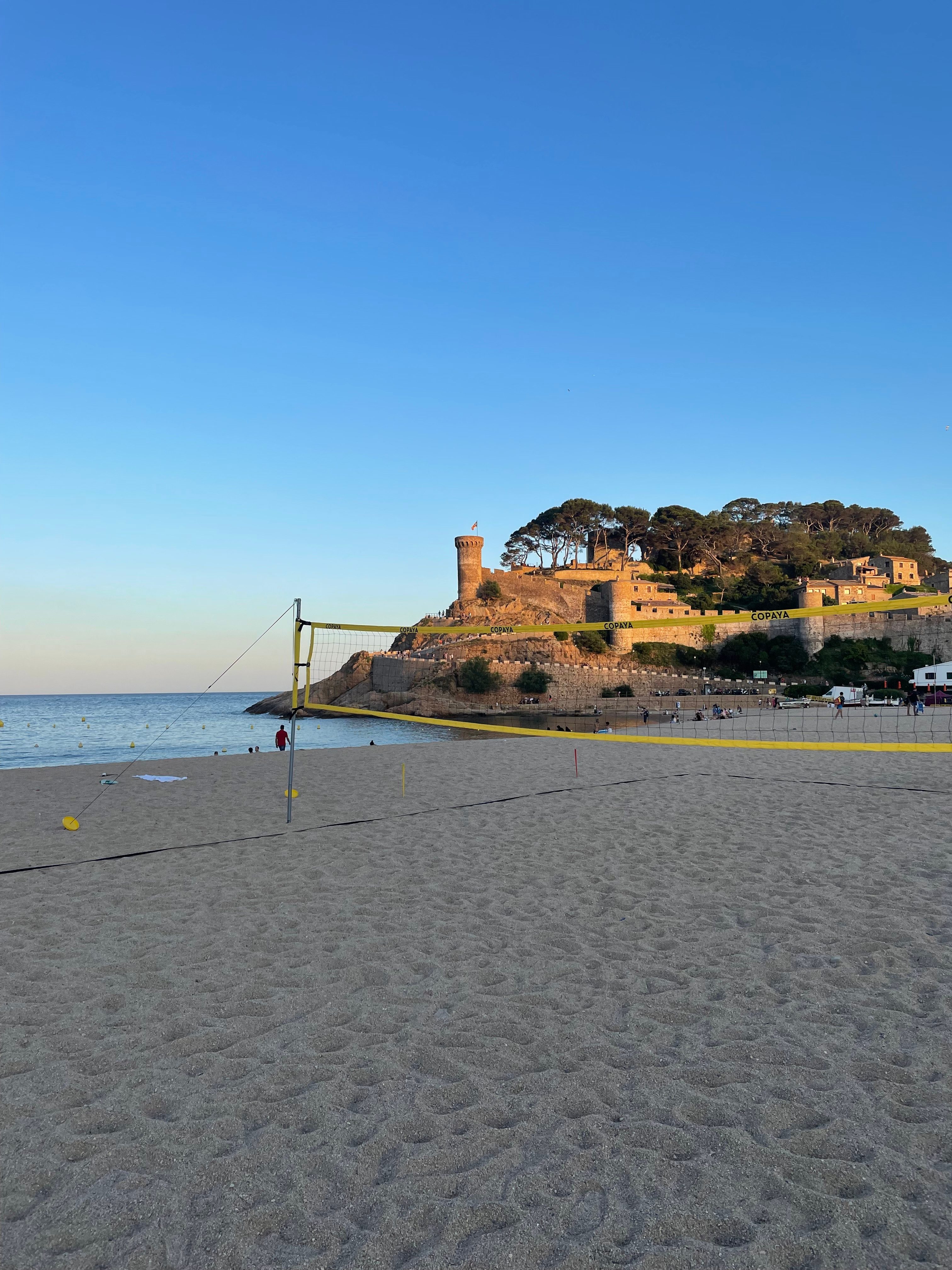 aufgebautes Volleyballnetz am Strand mit Burg im Hintergrund